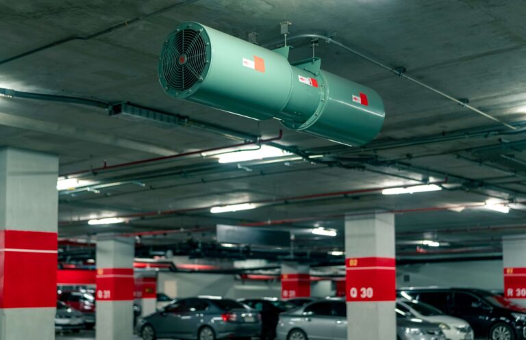 Kapalı otoparkta kurulmuş endüstriyel jet fanlı havalandırma sistemi ve park halindeki araçlar